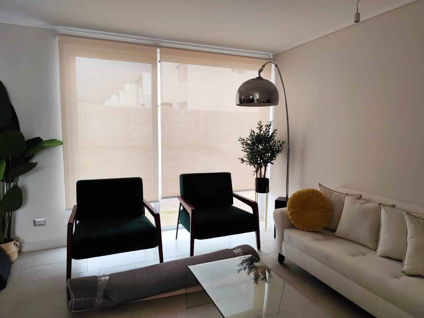 Living con cortina roller sunscreen bajada, sillones negros y sofá claro
