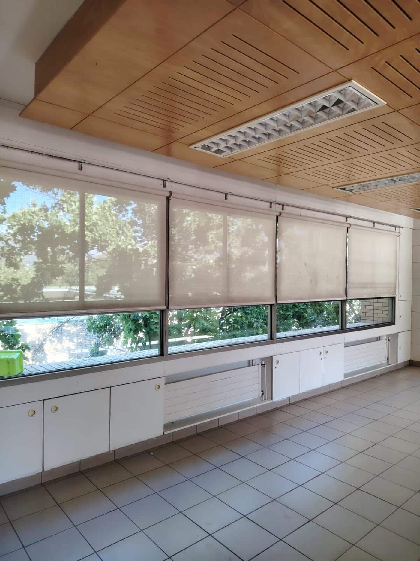 Sala amplia con cielo de madera y una corrida de cortinas roller sobre las ventanas