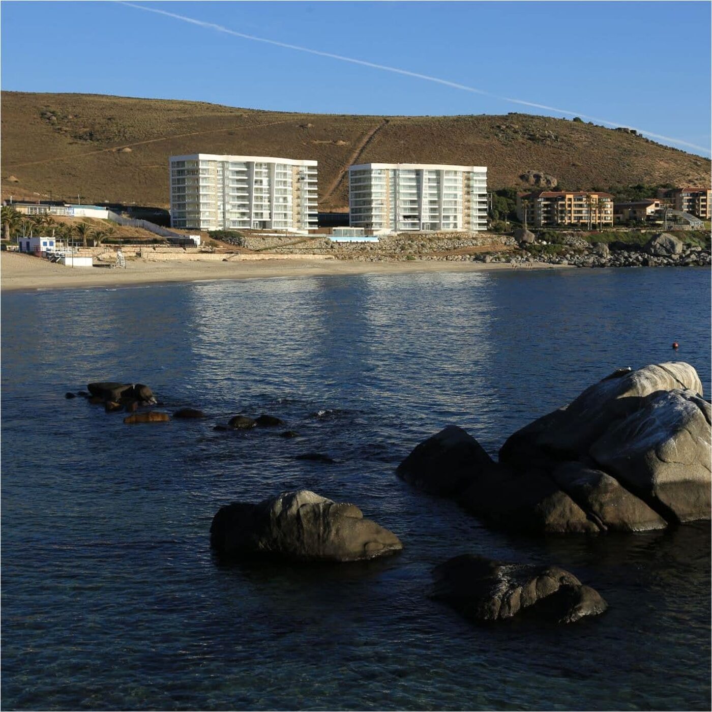 La playa y las rocas, con los edificios del condominio al fondo