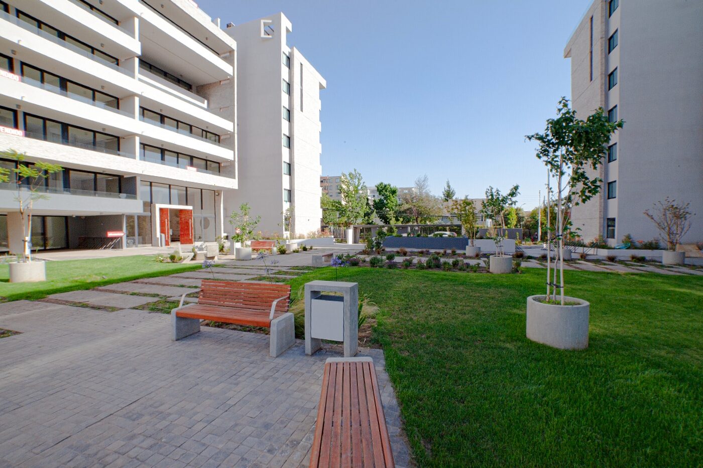Edificios del condominio Camargo Plaza con áreas verdes y bancas