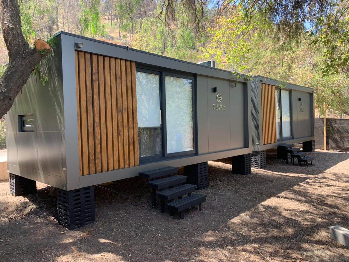 Módulo Tiny de Tecnofast en el bosque, con revestimiento de madera y ventanas corridas