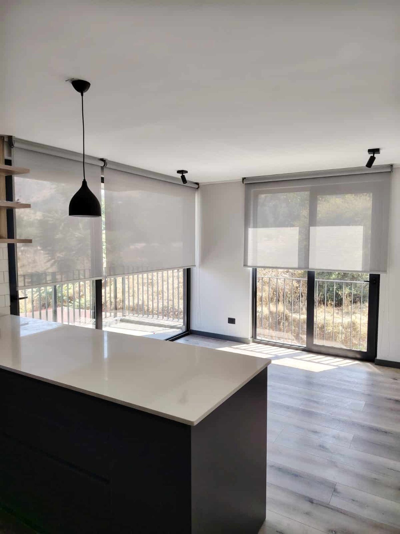 Living cocina con isla y cortinas roller sobre el ventanal con salida a balcón
